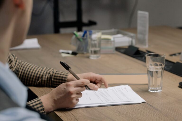 Mains posant un stylo sur des documents lors d'un rendez-vous de conseil