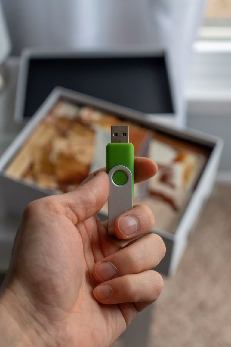 Clé USB posée près d'une boîte de vieilles photographies de famille