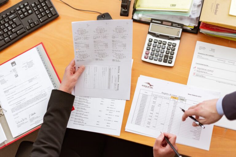 Personne à son bureau tenant une feuille et un stylo