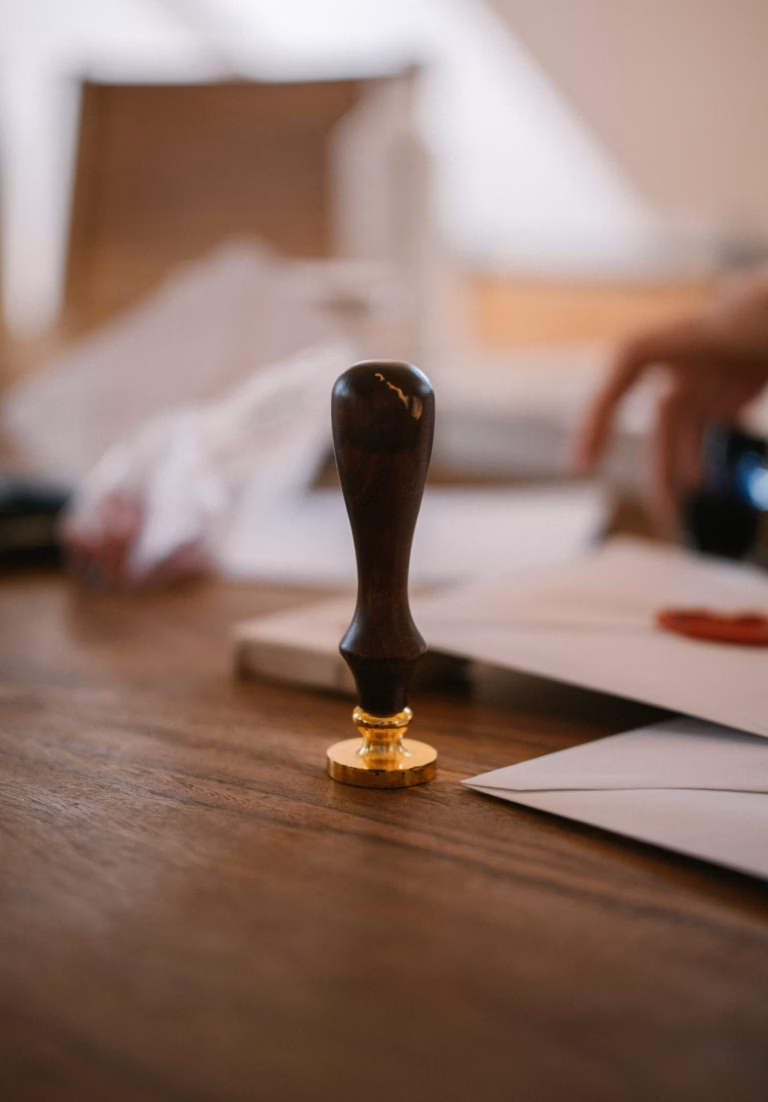 Cachet de cire ancien posé sur un bureau en bois à côté d'enveloppes